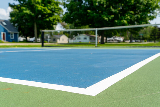 Recreational sport of pickleball or tennis court in the United States with green and blue court with blurred background.