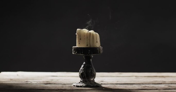 Video of halloween candle with smoke and copy space on wooden and black background