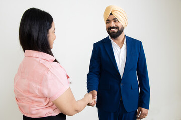 Young indian sikh business man shake hand with woman isolated over white background. Recruitment, Best job candidate, Diversity and ethnicity.  