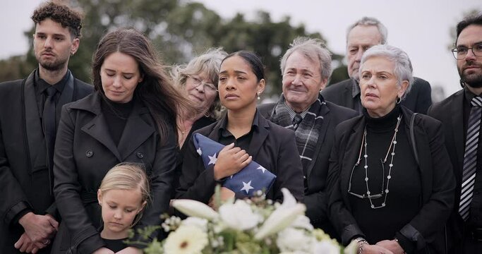 Funeral, cemetery and family with American flag for veteran for respect, ceremony and memorial service. Sad, depression and people by coffin in graveyard for military hero, army and soldier mourning