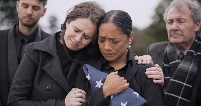 Funeral, death and support for a woman with a flag at a cemetery in mourning at a memorial service. Sad, usa and an army wife as a widow in a graveyard feeling the pain of loss or grief with a friend