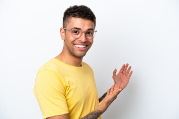 Young Brazilian man isolated on white background With glasses and presenting something