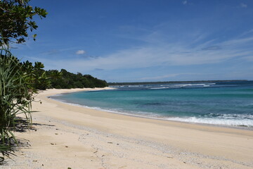 View of a wide beach in Indonesia with a clear blue sky and no people on it. 