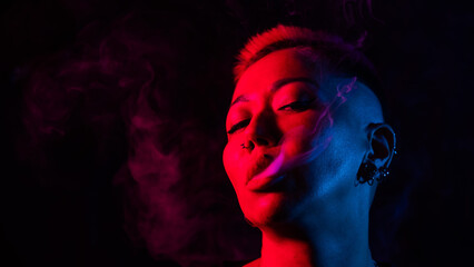 Close up portrait of asian woman with short hair smoking in neon light. 