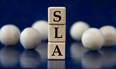 SLA - acronym on wooden cubes on a blue background with wooden balls
