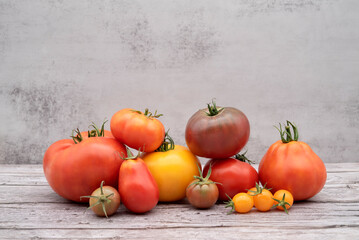 Collection of garden tomatoes. Superfood.
Pineapple tomato, cherry. Fresh tomatoes. Gray background, texture, wood.