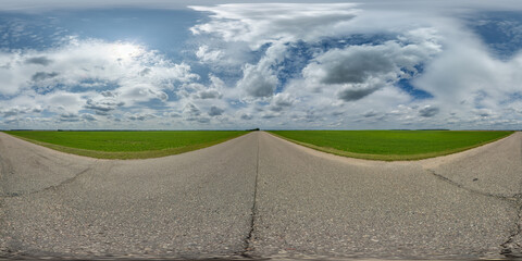 spherical 360 hdri panorama on old asphalt road with cracks with clouds and sun on blue sky in...