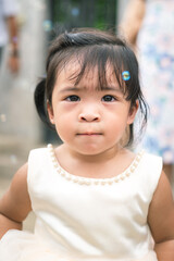 A cute little girl is white dress during playing air soap bubble with happiness action in the wedding event. Girl portrait photo, face focus.