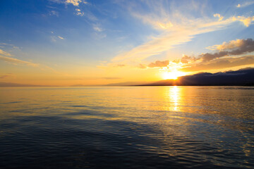 Obraz premium Colorful sunset on the sea. Mountain lake in the rays of the orange sun. Kyrgyzstan, Lake Issyk-Kul.