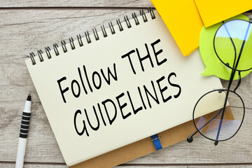 follow the guidelines open notebook with text near glasses. wooden background.