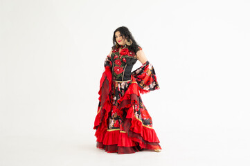 A young girl demonstrates a smart elegant red dress. Flamenco clothing. Gypsy romale style. Professional dancer isolated on white background.