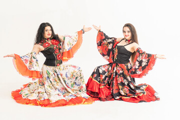Two beautiful girls posing in elegant dresses. Flamenco dancers footage. Gypsy romale style. Professional dancer isolated on white background.