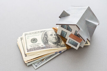 Wooden house model on background of US dollars banknotes. Housing market, purchase or rental of...