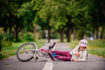 Little girl of school age fell off her bike and cries