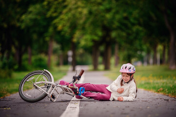 Little girl of school age fell off her bike and cries