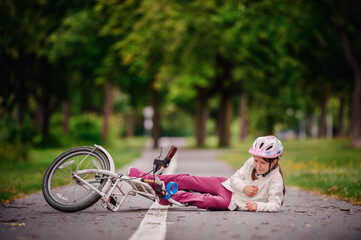 Little girl of school age fell off her bike and cries