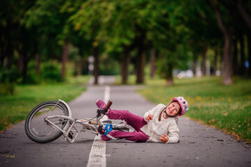 Little girl of school age fell off her bike and cries