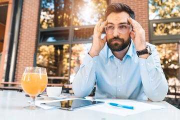 Worried businessman sitting at caffe and is thinking hard about new ideas and solutions for the...