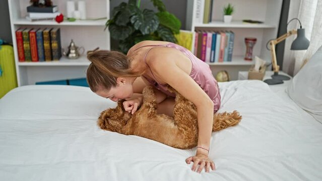 Young caucasian woman with dog sitting on the bed together playing at bedroom