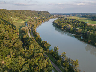 Aerial view of Inn river and forest during summer sunset near Inn river in Marktl, road and railroad next to river