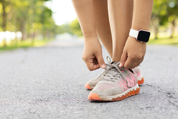 Runner woman tying Running shoes laces for preparing for a run a jog outside. Jogging girl exercise motivation heatlh and fitness. Active asian runner woman tying shoe lace before running.