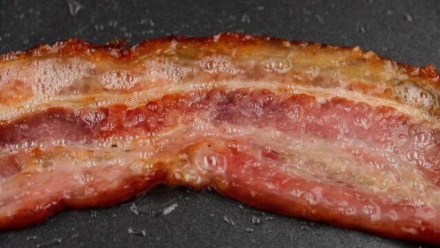 Sliced bacon fried in pan, zoom frame