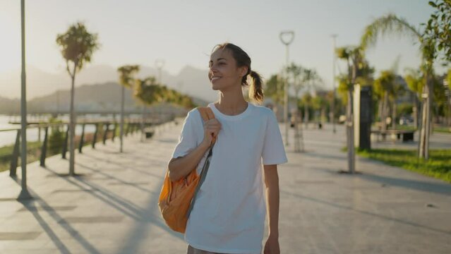 young happy Woman traveler walking bay sidewalk and watching sunset or sunrise with mountains and sea view. Tourism in Turkie, Antalya. active leisure, wanderlust and traveling