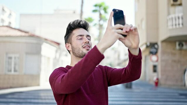 Young hispanic man smiling confident recording video by the smartphone at street