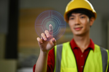 Asian male warehouse worker pressing button on virtual screen. Future technology and inventory management concept