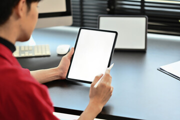 Rear view of startup businessman using digital tablet on dark wooden office desk