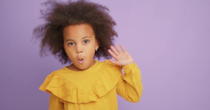 naughty adorable cute black girl makes faces Child girl makes funny faces and grimaces, close-up Slow motion, kid is dancing in studio purple background Slow motion