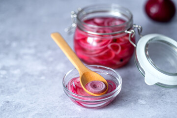 Homemade pickled red onions rings in glass jar on a gray background. Fermented vegetarian food concept. Healthy eating. High quality photo