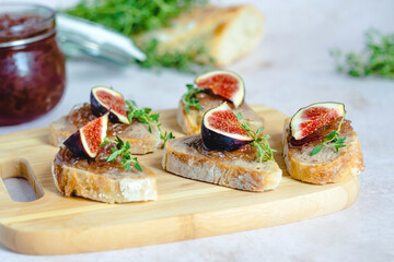 Homemade caramelized figs with onion bruschetta, fresh thyme served on a wood serving board. Healthy organic food.