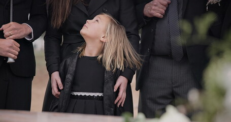 Mourning, grief and family with girl at funeral, flowers on coffin, death and sad child at service...
