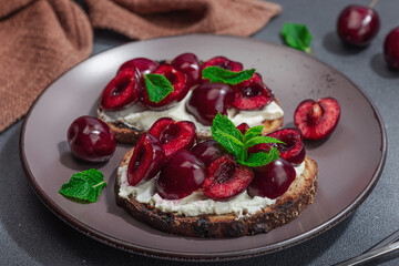 Fresh bread sandwiches with sweet cherry, cream cheese and mint leaves. Morning breakfast concept