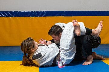 Young girl and boy practice Brazilian jiu jitsu in the gym