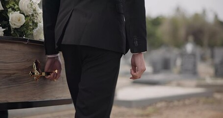 Coffin, hands and man walking at funeral ceremony outdoor with pallbearers at tomb. Death, grief and person carrying casket at cemetery, graveyard or family service of people mourning at windy event