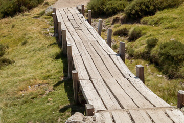 Fototapeta na wymiar Sendero construido con tablones de madera en la Sierra de Gredos, Ávila, España. Paso de madera construido para pasar por encima de una zona de turbera.