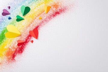 LGBT history month tribute in sand flag. Top view reveals a rainbow sand flag and little hearts on...