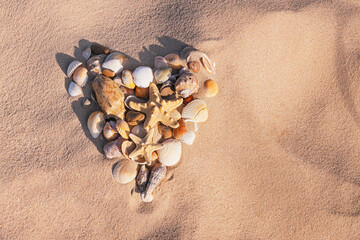 A heart made of seashells on a background of sand.