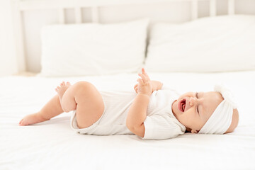 a crying little baby on a white bed at home, a sick child crying and screaming and calling for mom