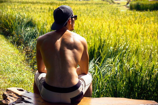 Photo of a man enjoying the peacefulness of nature while sitting on a bench in a scenic field