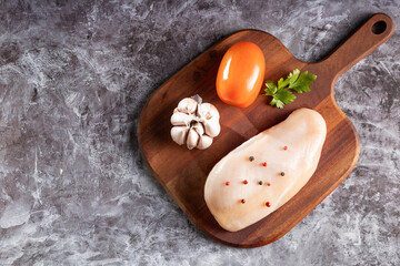 Fresh raw chicken breast with ingredients for cooking.