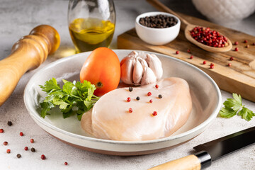 Fresh raw chicken breast with ingredients for cooking.