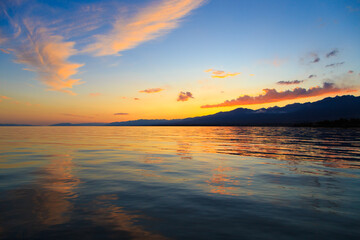 Beautiful cloudy sunset over the sea and mountains. Bright sky in the rays of the orange sun. natural texture