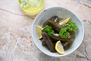 Grey bowl with greek dolma or dolmadakia on a pinkish granite background, elevated view, horizontal shot with space