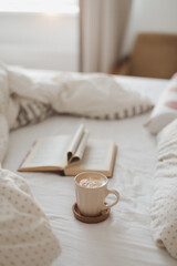 Cozy morning composition with a coffee cup and a book with pages folded into a heart shape in bed