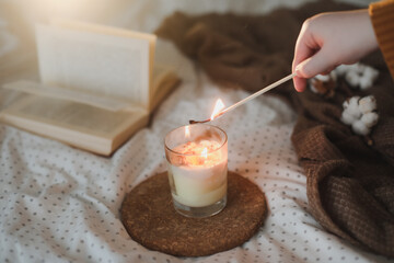 Details of still life in the home interior of living room.Cotton, cozy, book, candle. Moody. Cosy autumn winter concept. Decoration, vintage with glow bokeh.