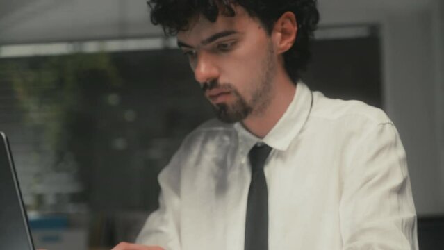 Tilt up shot of young businessman typing emails on keyboard of laptop when preparing for meeting sitting at office at night timeTilt up shot of young businessman typing emails on keyboard of laptop wh