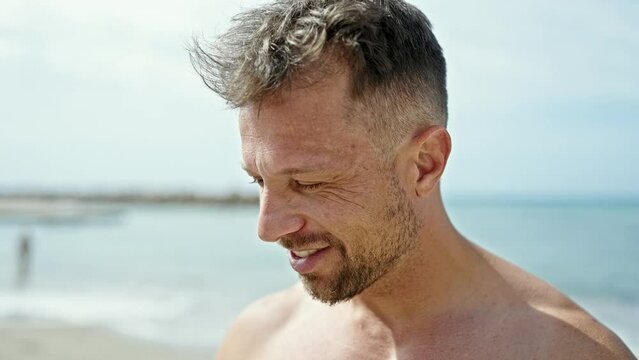 Young man tourist smiling confident combing hair with hands at the beach